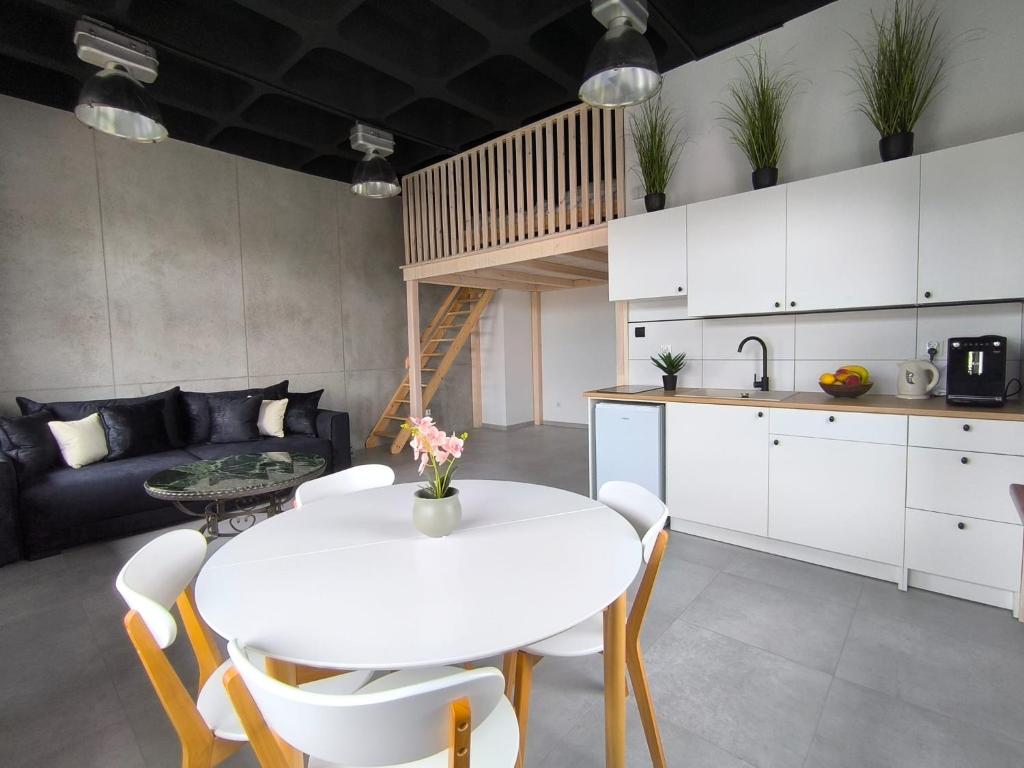 a kitchen and living room with a white table and chairs at Apartament Antresola in Ostróda