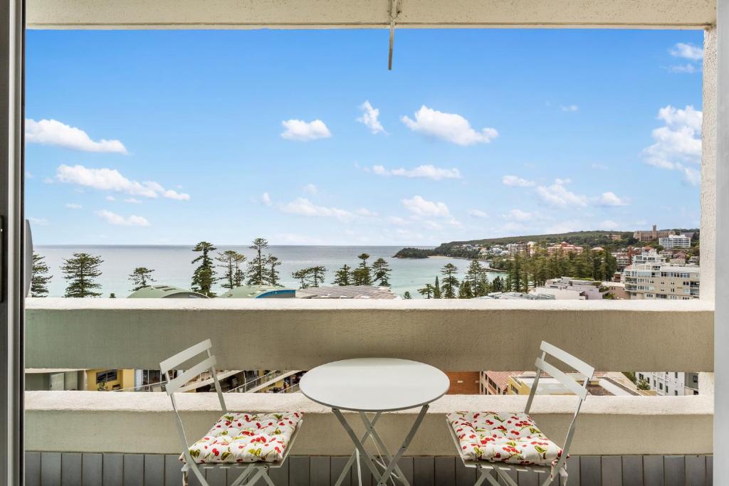 a balcony with a table and chairs and a view of the ocean at Apartment with Pool Access a minute to the Beach in Sydney