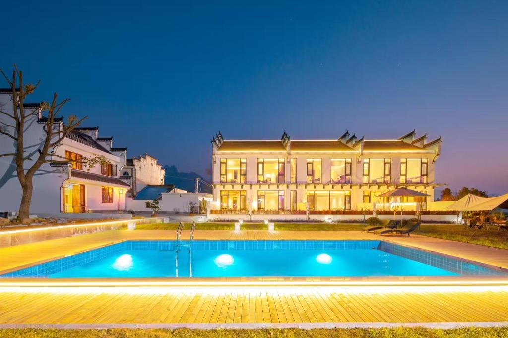 una casa con piscina delante de un edificio en Huazhushe Jiuhuashan Suli Zhuyunjian B&amp;B, en Chizhou