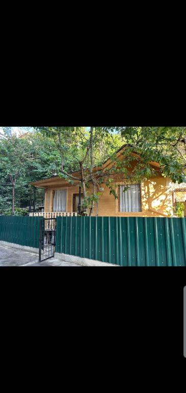 a house with a green fence in front of it at Temos cottage in Borjomi