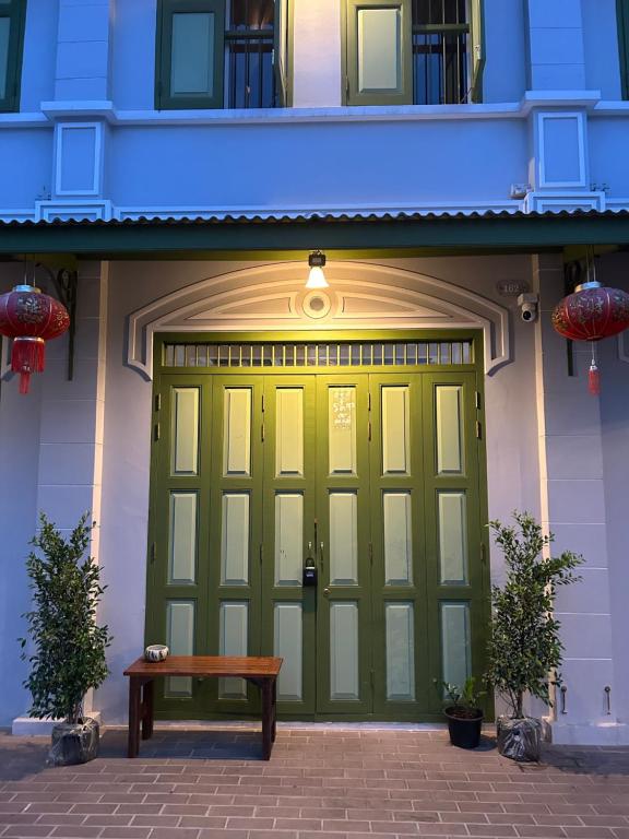 Una puerta de garaje verde con un banco delante de ella. en Mookda House Chinatown BKK near MRT Samyot, en Khlong San