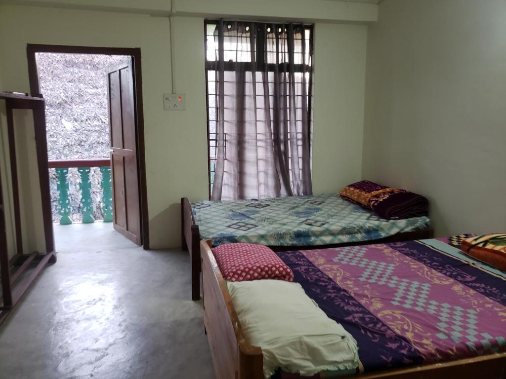 two beds in a room with a window at Luhngam Homestay in Mon