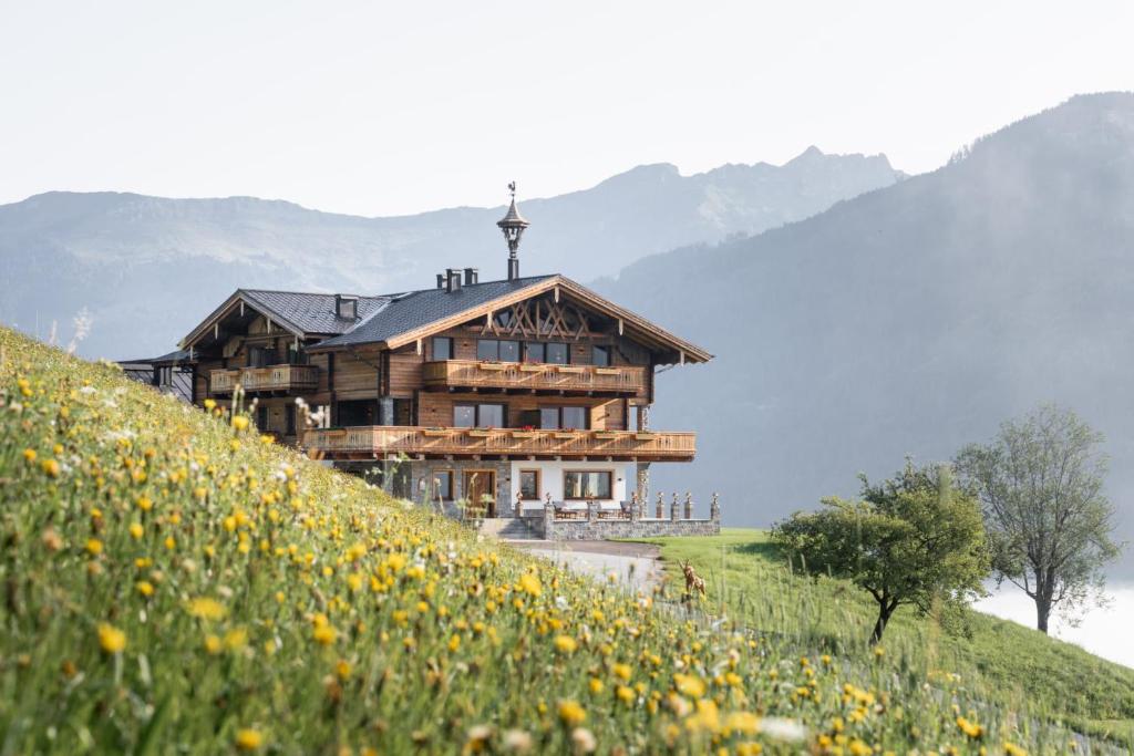 a house on top of a hill with a field of flowers at Das Grabnergut in Bad Hofgastein