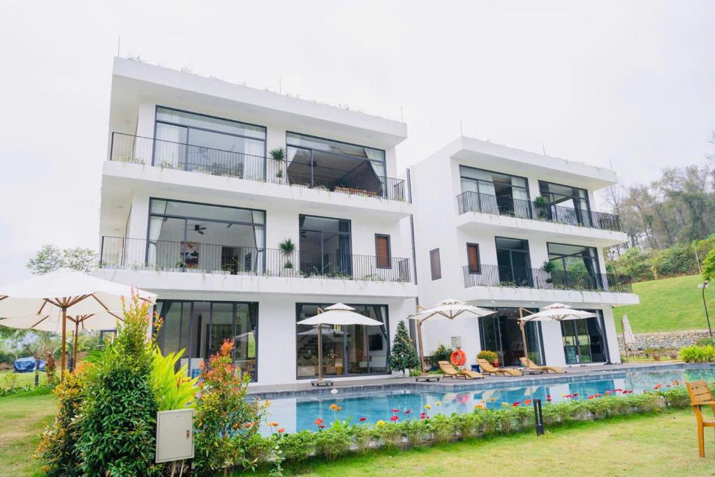 a white building with a swimming pool in front of it at Rolling Hill Resort in Xóm Trông