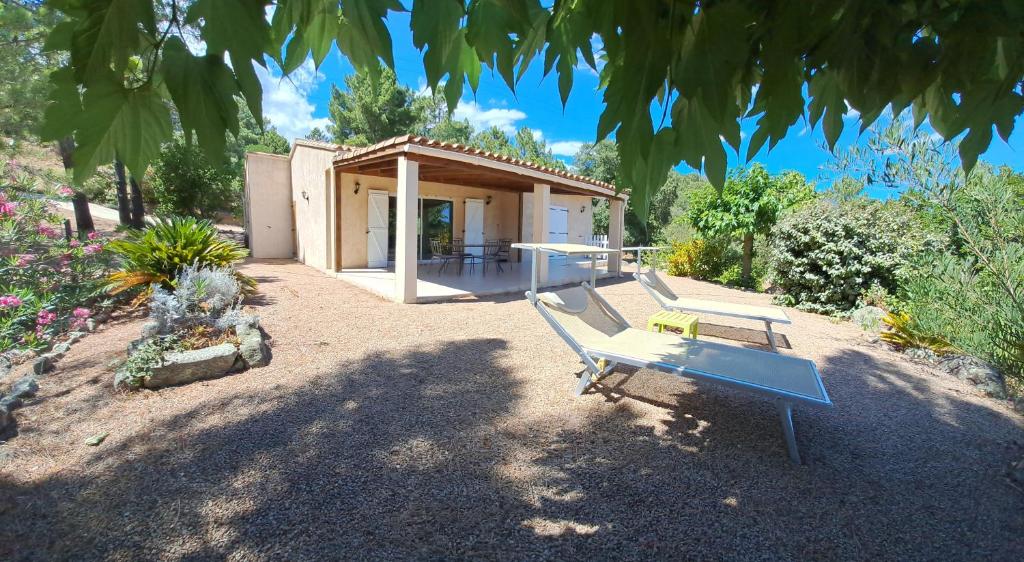 una panchina seduta di fronte a una piccola casa di Villa avec piscine hors sol à 10mn de la plage a Lecci