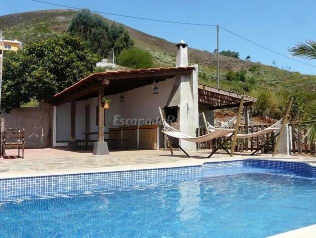 una piscina con 2 sillas y una casa en Casa Domi, en La Esperanza