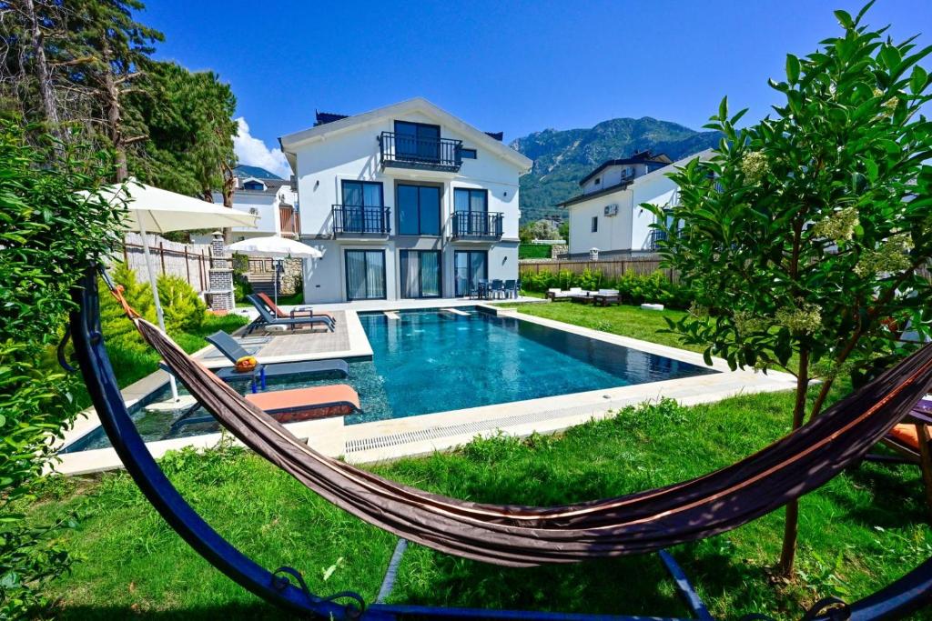 a hammock in front of a house with a swimming pool at Aura luxury-Modern Stylish Central Holiday Villa For 6 Peeople in Fethiye