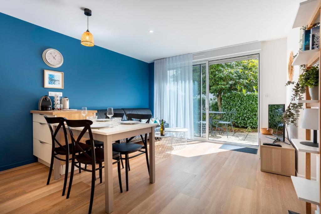 a kitchen and dining room with blue walls and a table and chairs at L’Escale – Tout à pied à Ste-Marine in Combrit