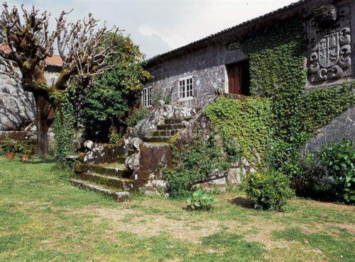 un edificio cubierto de hiedra con escaleras delante de una casa en Palacio de Barreiro, en Crecíente