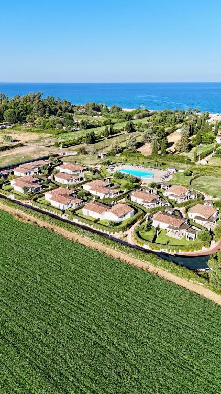 an aerial view of a resort with a field and the ocean at Ville d'Ogliastra 2 - Marina Suites in Cardedu