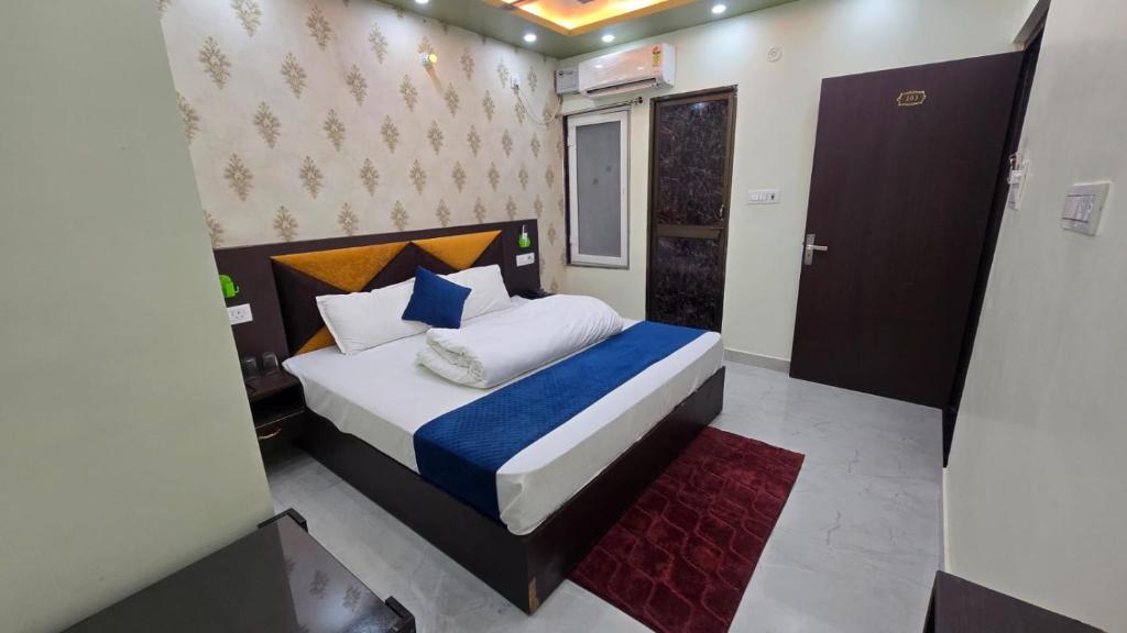 a bedroom with a large bed with blue and white pillows at Hotel Ramayanam palace in Ayodhya