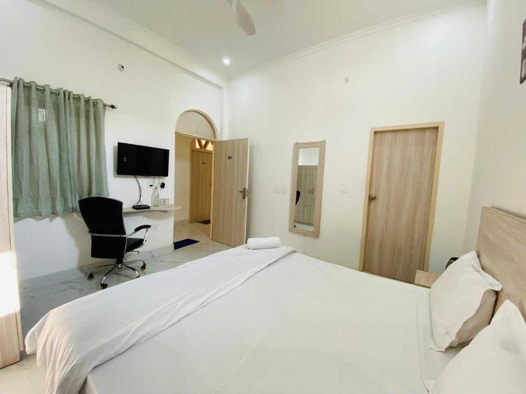 a white bedroom with a large bed and a desk at Hotel O Dehradun Railway Station Formerly Vista Express Homestay in Dehradun