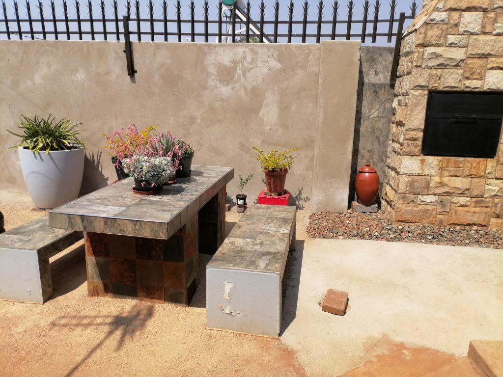 a patio with two benches and potted plants at Black Oyster in Vosloorus