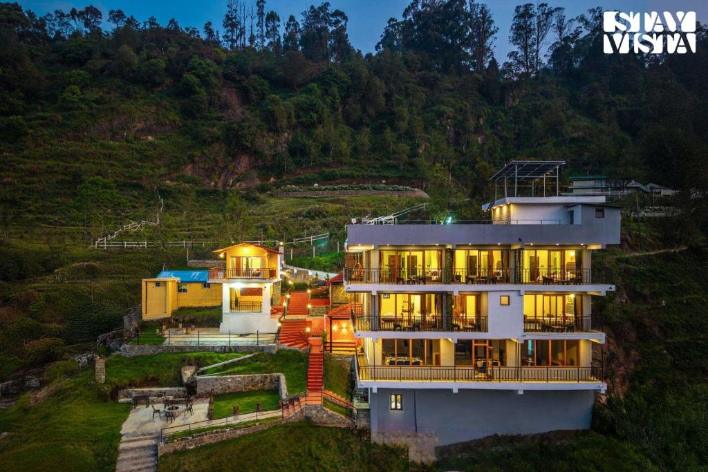 a large house with lights on top of a hill at StayVista at Kurinji Amaze Kodai with WiFI & Heater in Kodaikānāl
