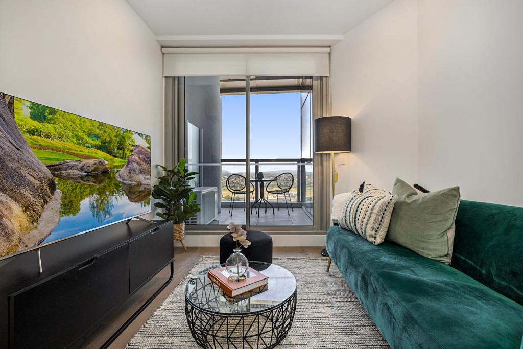 a living room with a green couch and a tv at High-Rise Balcony Unit with City Views Gym Pool in Melbourne