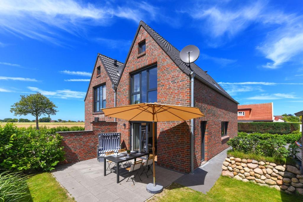 a brick house with a table and an umbrella at Ferienhaus Fischerstuuv in Carolinensiel