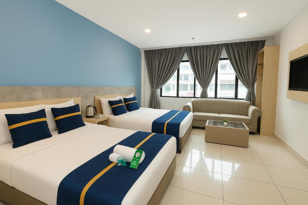 a hotel room with two beds and a couch at StarQ Hotel in Kuala Lumpur