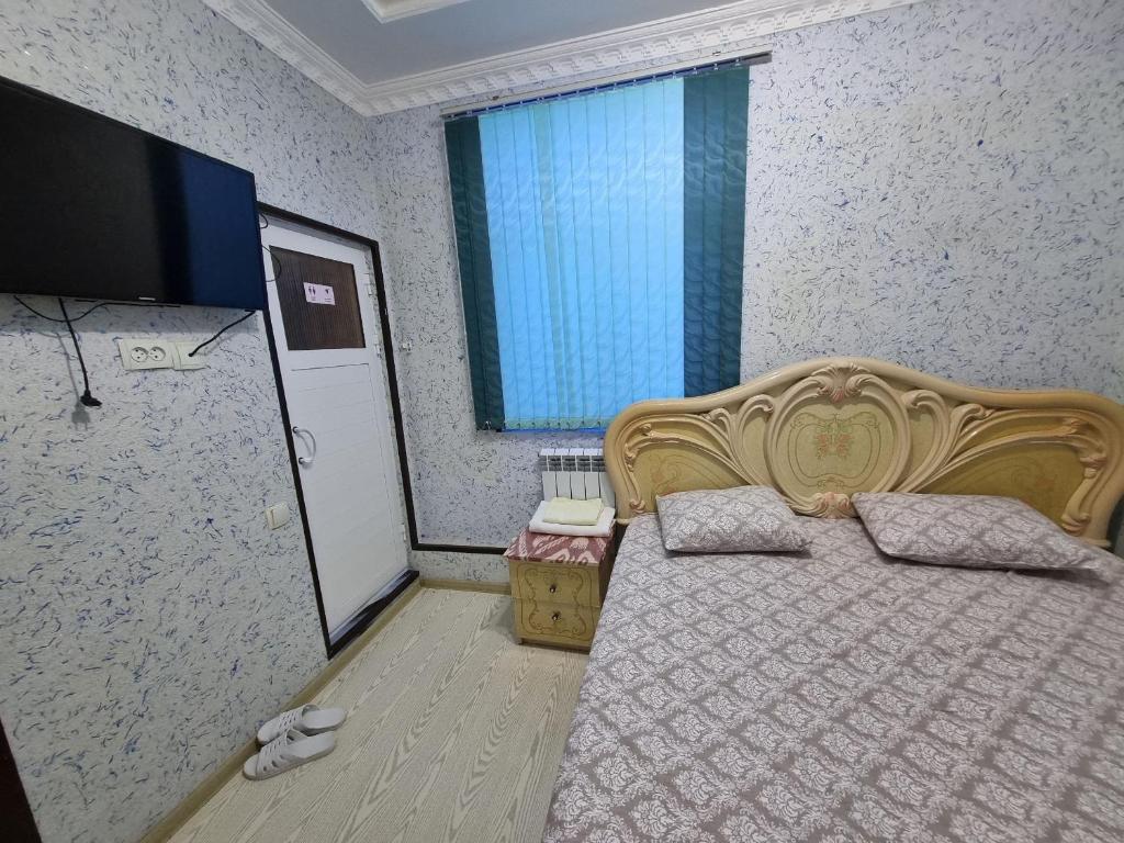 una camera da letto con un letto e una TV a schermo piatto di Nastarin a Bukhara