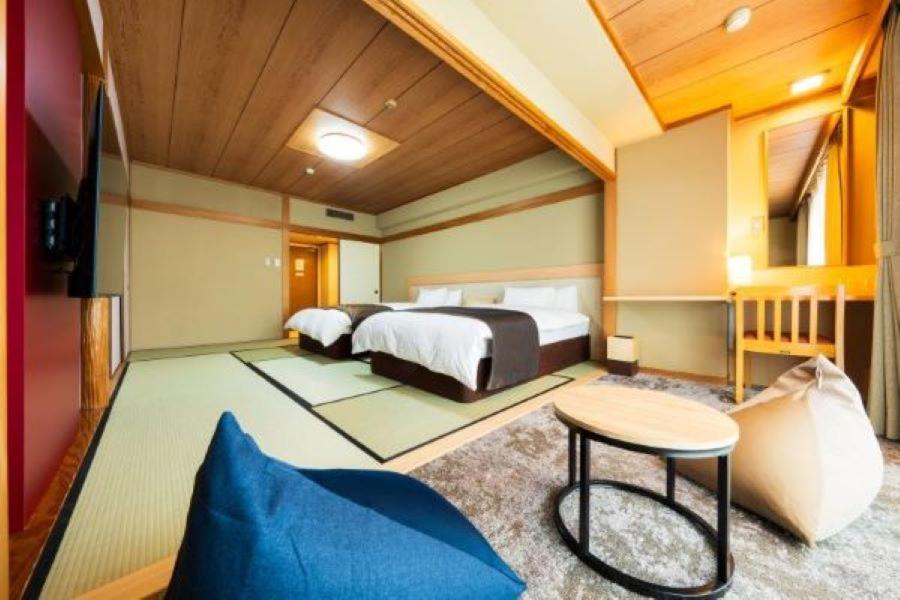 une chambre avec un lit et une table dans une pièce dans l'établissement Shiragiku, à Beppu