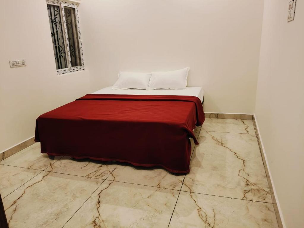 a bed with a red blanket on top of a marble floor at Rudraksha RESIDENCY in Tiruvannāmalai
