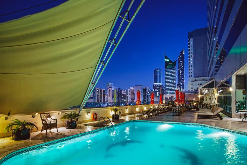 einem Pool auf einem Gebäude mit Skyline der Stadt in der Unterkunft Corniche Hotel Abu Dhabi in Abu Dhabi