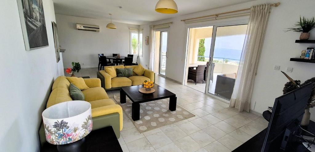 Una sala de estar con un sofá amarillo y una mesa. en Romanson Seaview Apartment, en Kissonerga