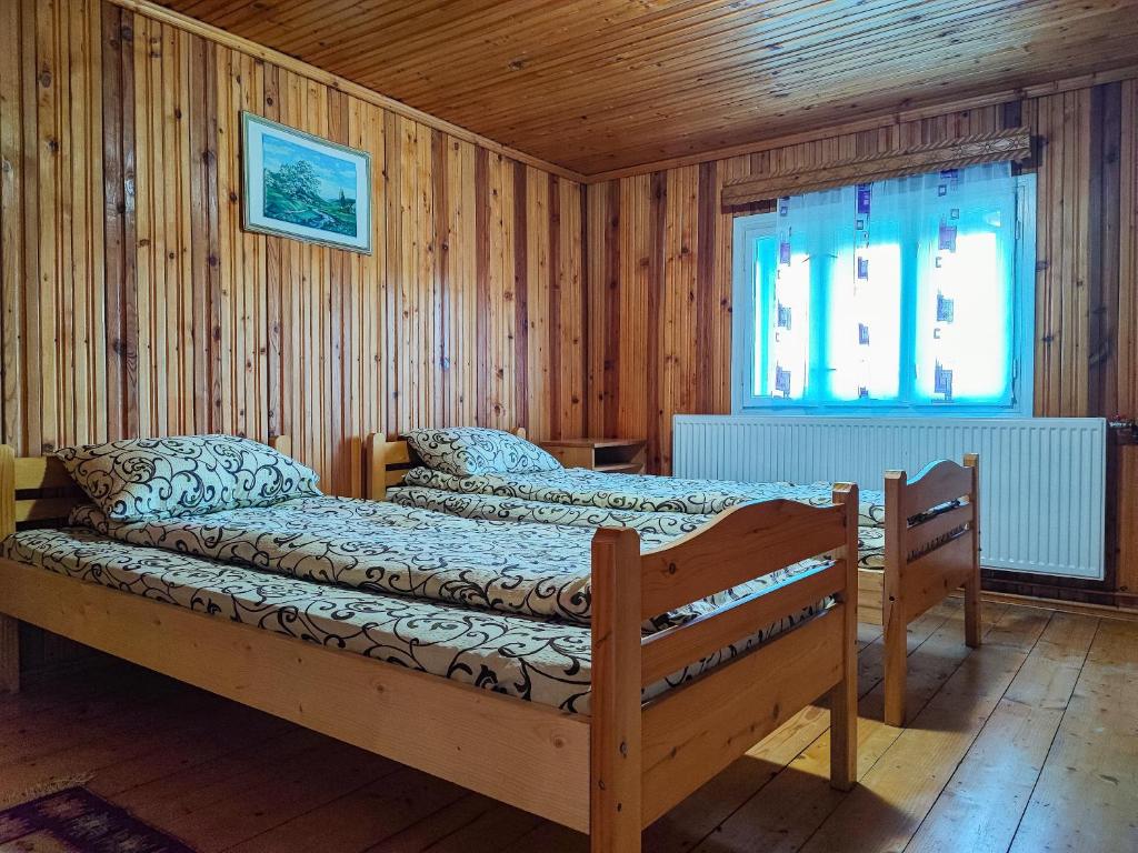 a bedroom with two beds in a room with wooden walls at Cabana Georgiana Dealu Negru in Dealu Negru