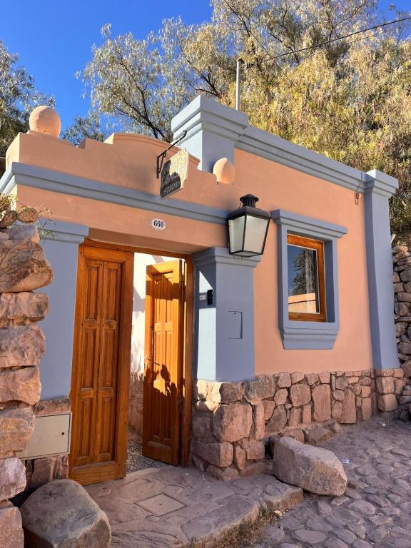 a small house with a wooden door and a stone wall at Quinta La Paceña in Tilcara