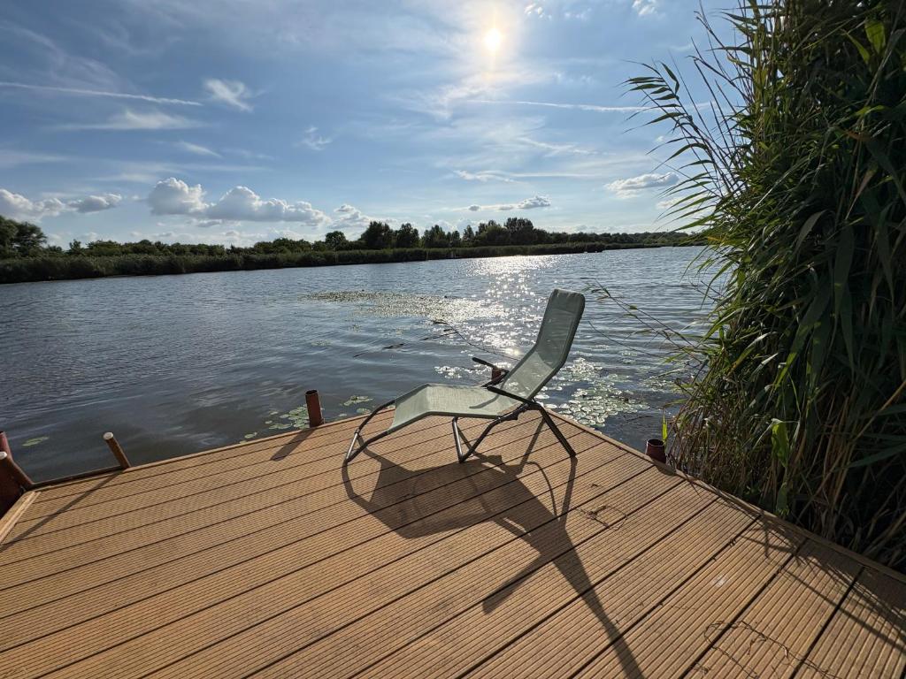 a chair sitting on a dock next to the water at Viola Horgász-és Vendégház in Tiszaug