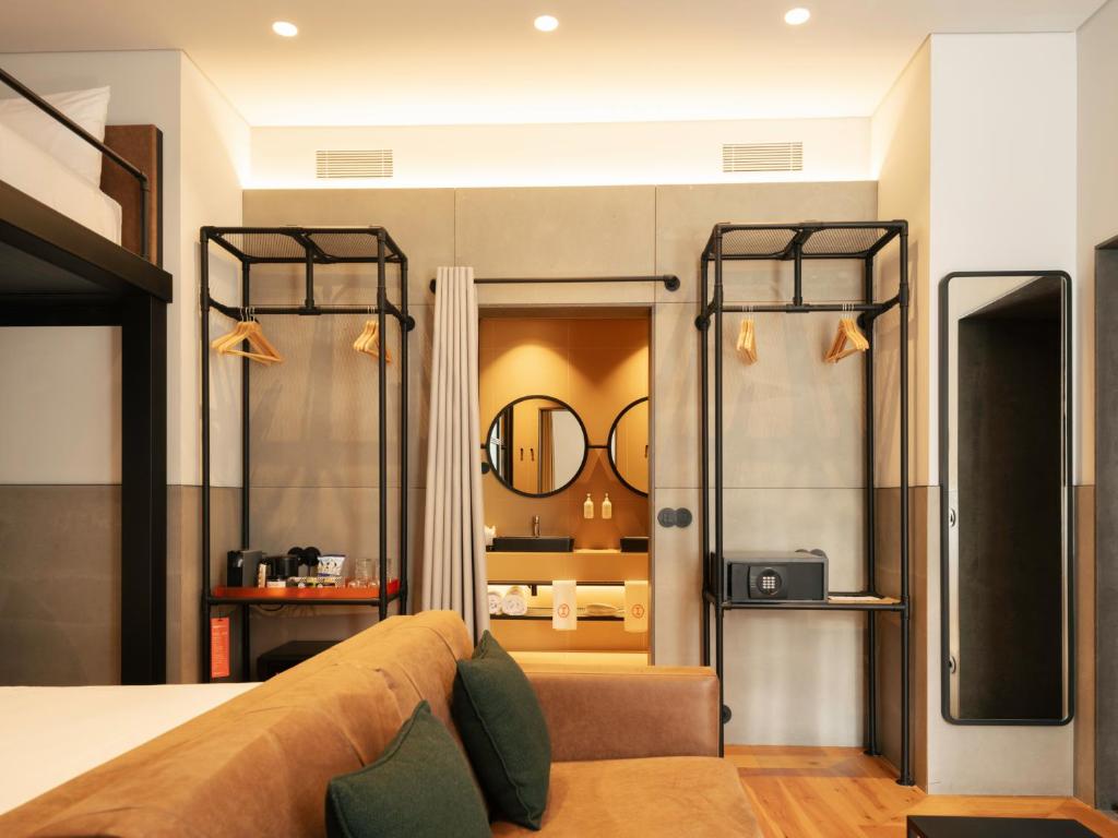 A stylish bedroom with a sofa, open clothes rails, and a bathroom beyond.