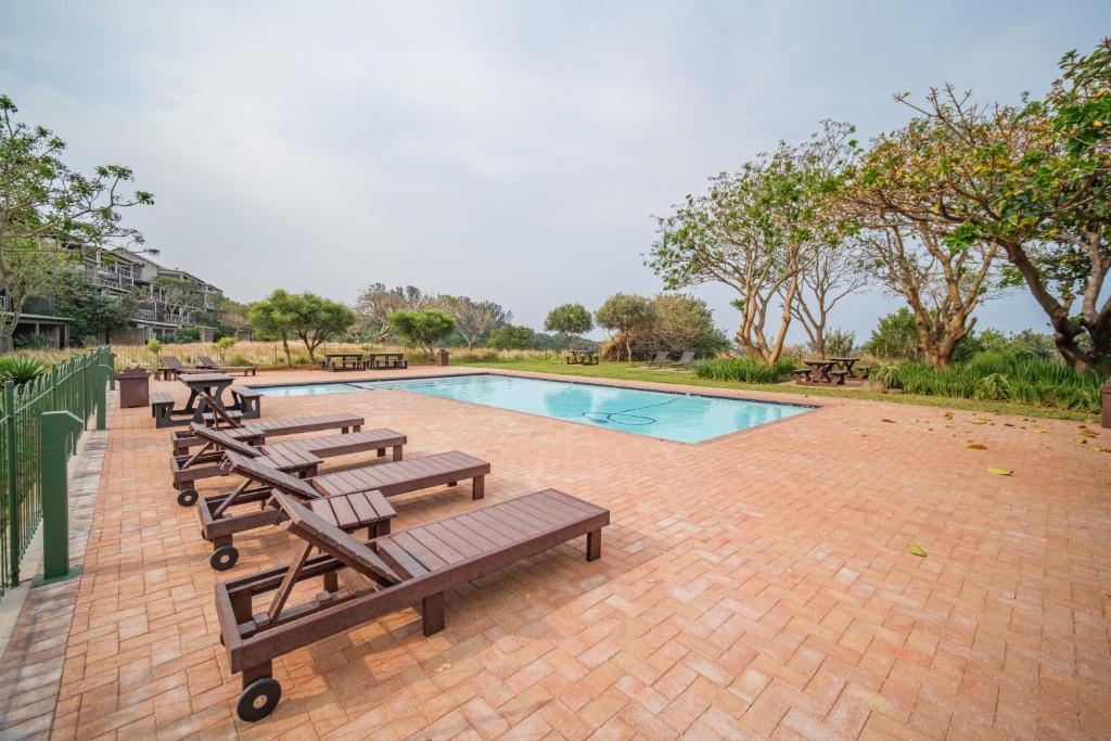 a pool with picnic tables and benches next to it at 17 Tamboti, Simbithi Eco Estate in Ballito