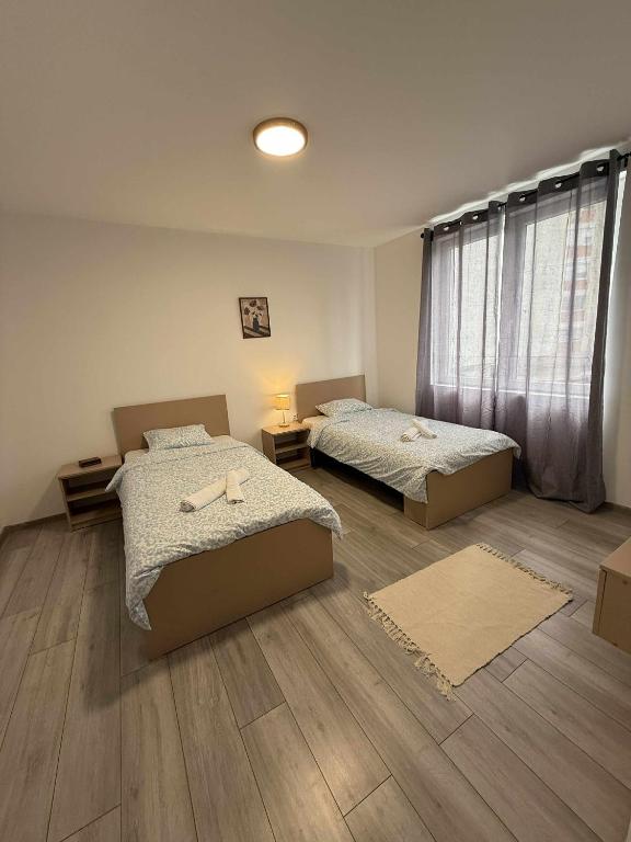 two beds in a room with wooden floors at Apartman MATEA in Pirot
