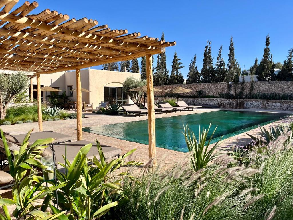 a swimming pool in a backyard with a wooden pergola at Maison Flamingo - Boutique hôtel in Essaouira