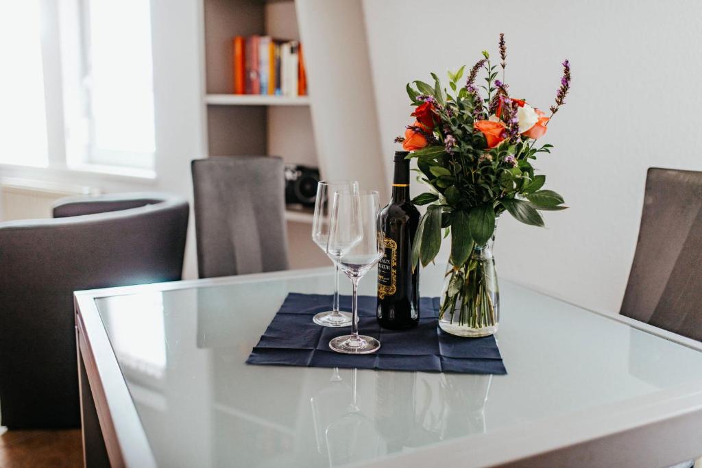 a table with two wine glasses and a vase of flowers at Ferienwohnungen Krampert in Bad Kissingen