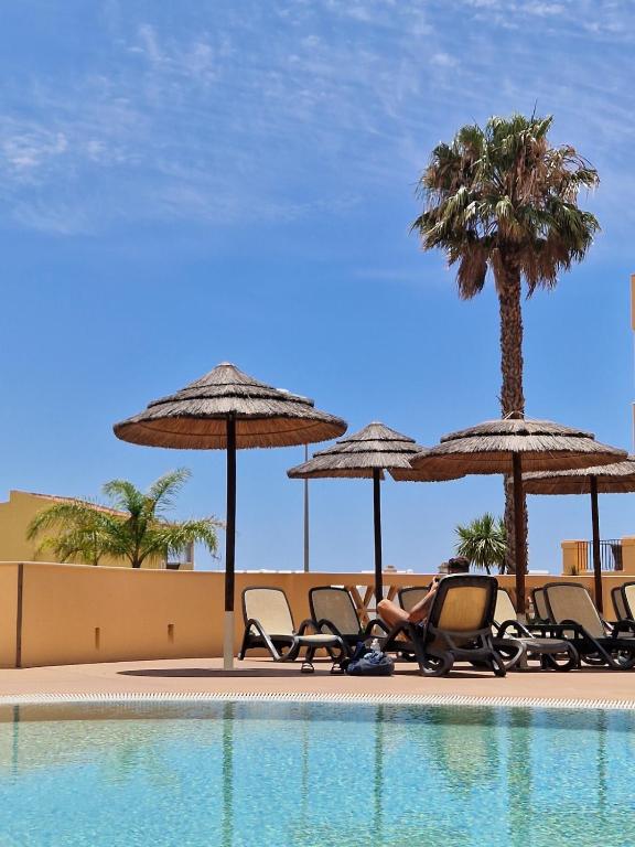 a group of chairs and umbrellas next to a pool at Estréla da Luz CasaValerie studio with gym and indoor pool in Luz