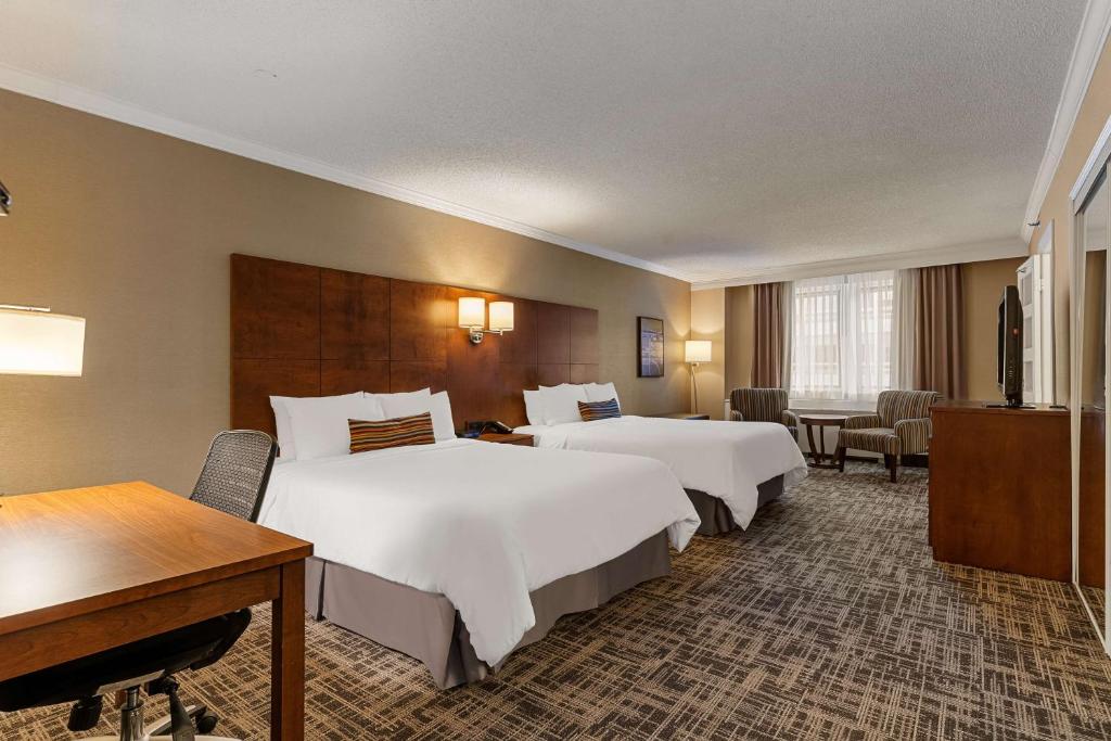 a hotel room with two beds and a desk at Best Western Ville-Marie Montreal Hotel & Suites in Montreal