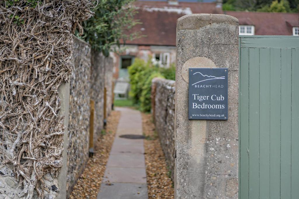 un cartello su una recinzione in pietra con un bagno del club degli alberi di Cub Bedroom Five a Eastdean