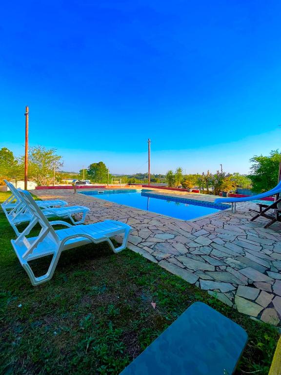 a pair of lounge chairs next to a swimming pool at Chácara Roteiro do Vinho com Wi-Fi in São Roque