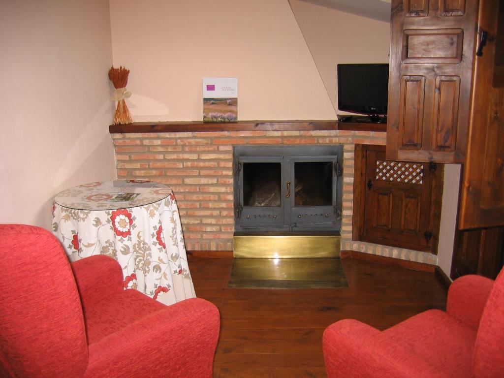 sala de estar con chimenea y sillas rojas en Hotel de Montaña Cueva Ahumada, en Villaverde de Guadalimar