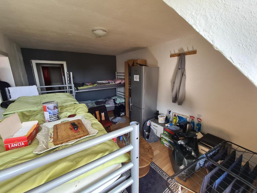 a bedroom with a bed and a refrigerator in a room at ein Platz im Etagenbett im Durchgang in Schalke Nähe Arena in Gelsenkirchen
