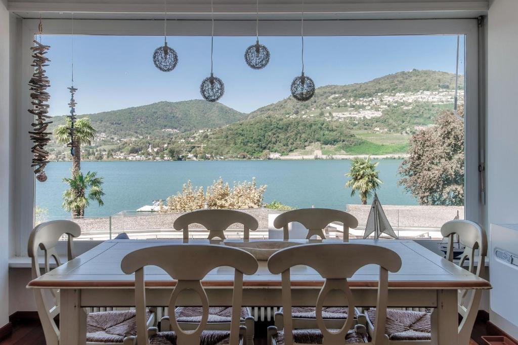 a dining room table with a view of a lake at Kümin Lake View by Quokka 360 - with direct access to the lake in Collina d'Oro