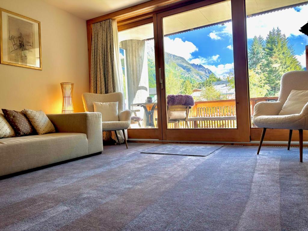 Una sala de estar con un sofá y una ventana grande. en Alpine Studio Apartment, en Maloja