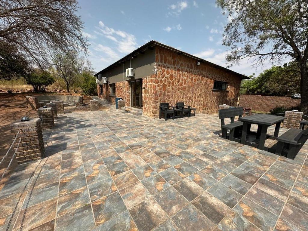 un patio de piedra con bancos y un edificio en Impala Game Ranch, en Dinokeng Game Reserve