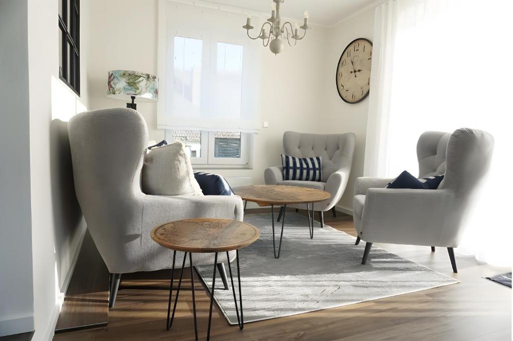 sala de estar con sillas, mesas y reloj en Ferienwohnung Jost, en Allendorf