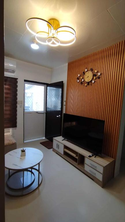 a living room with a tv and a table and a clock at Danielle's Haven in Naga