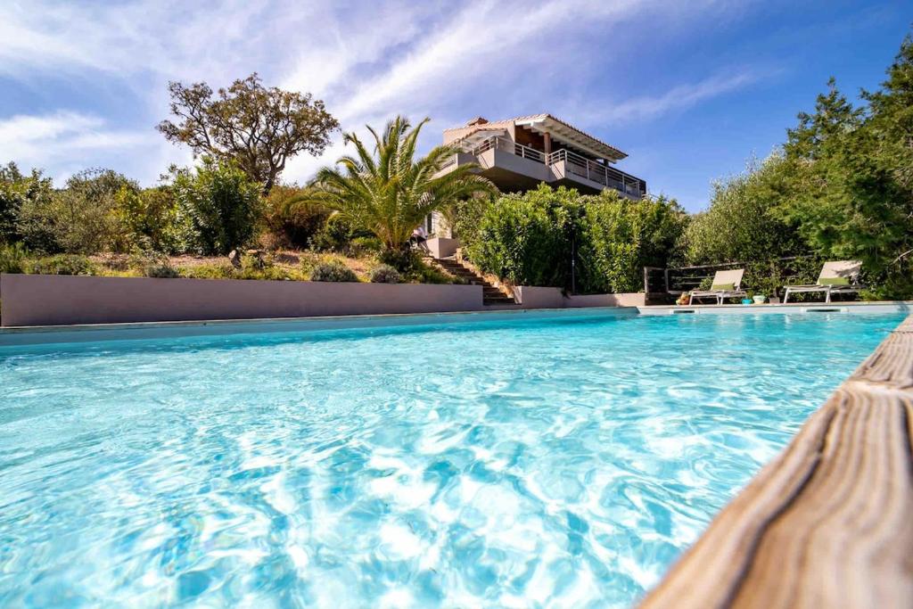 a large swimming pool with a house in the background at magnifique maison vu mer 5 ch in Porto-Vecchio