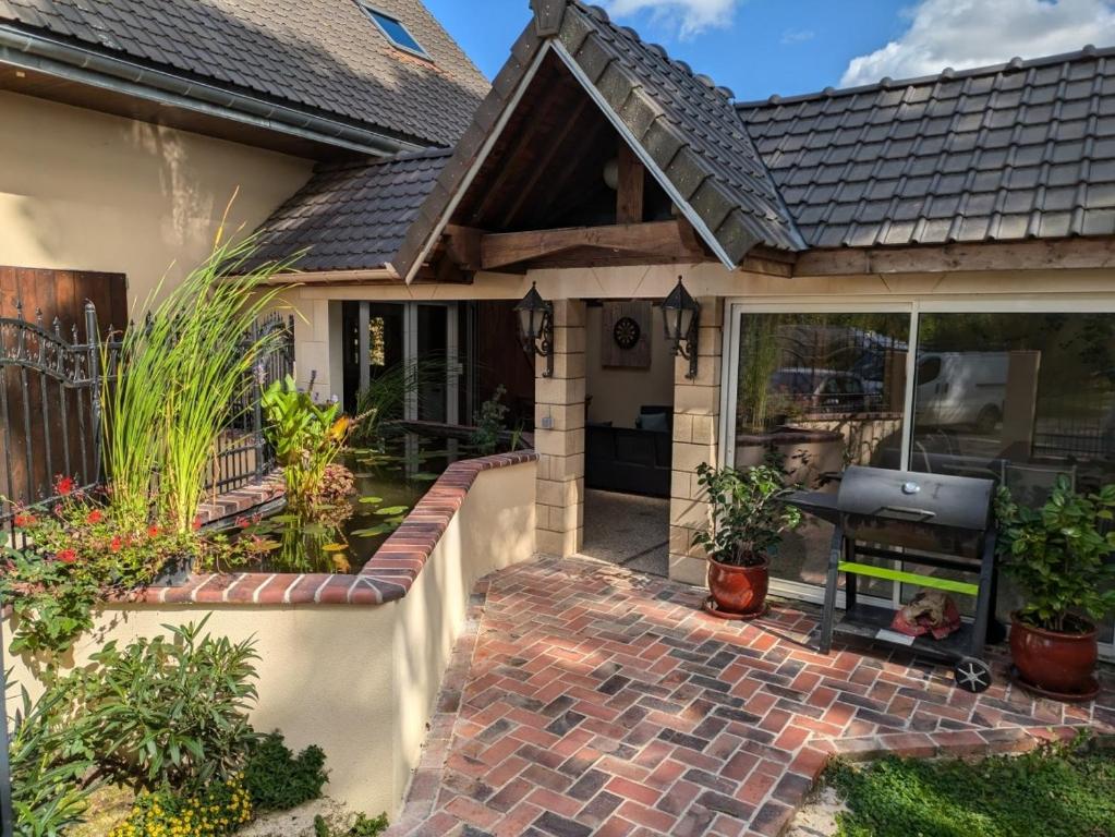 a house with a brick patio with a grill at Au coeur de nos campagnes in Lachapelle-Saint-Pierre