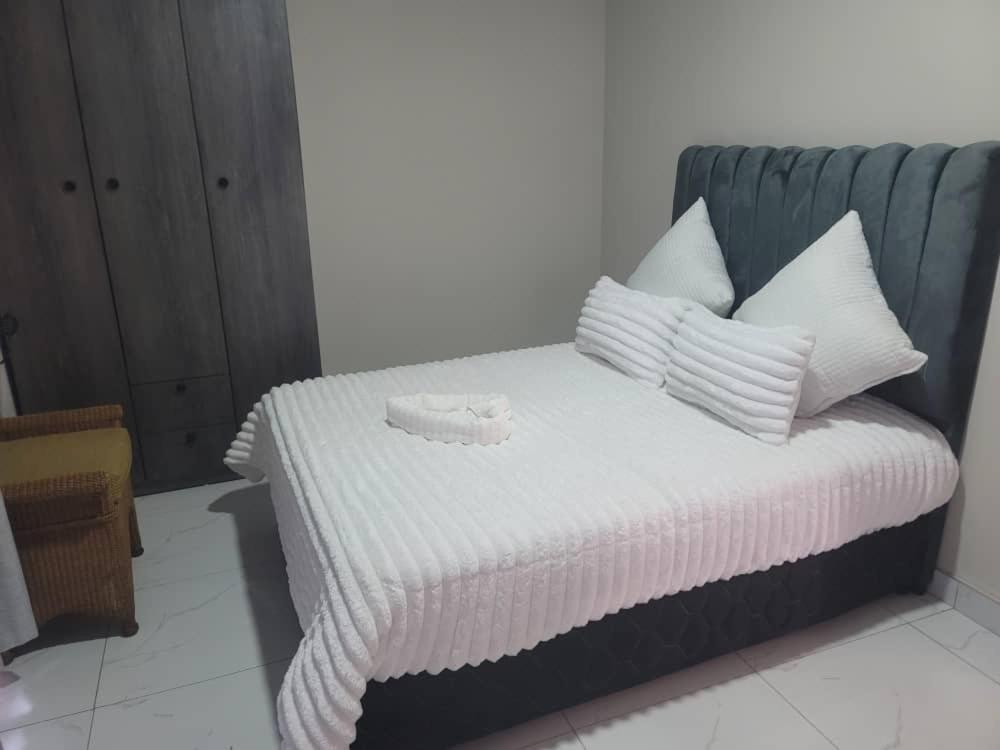 Una cama con sábanas blancas y almohadas en una habitación. en Tou Safari Lodge, en Livingstone