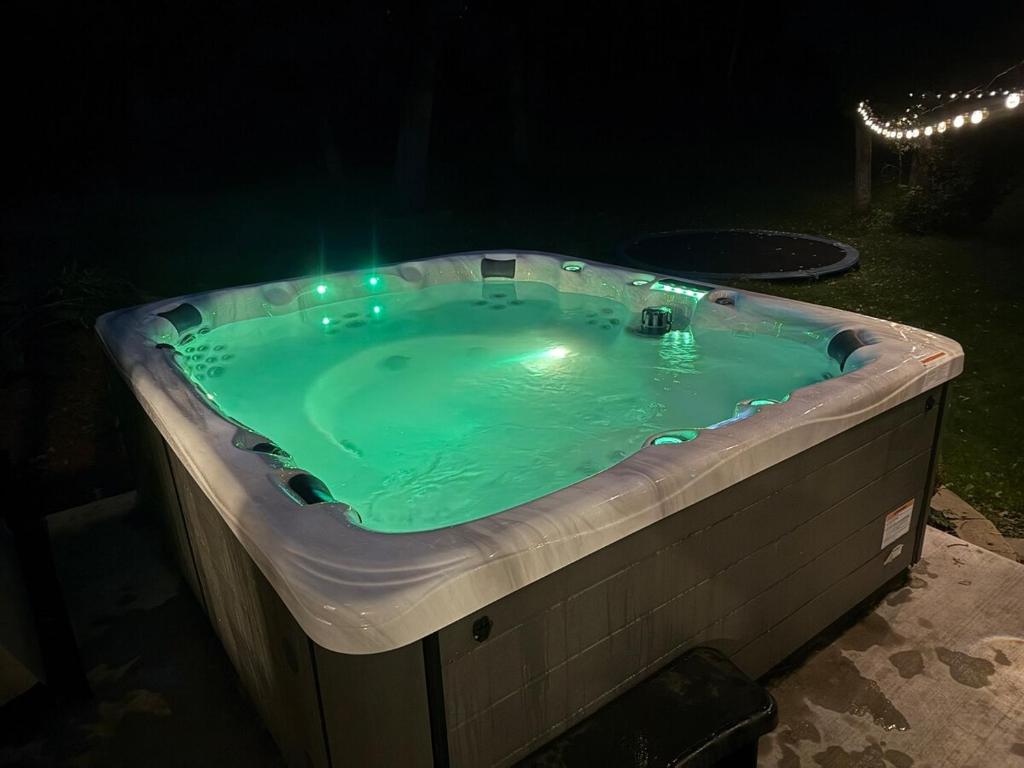una bañera de hidromasaje en un patio trasero por la noche en Spacious 5BR Getaway, Hot Tub, Cozy Vibes, 