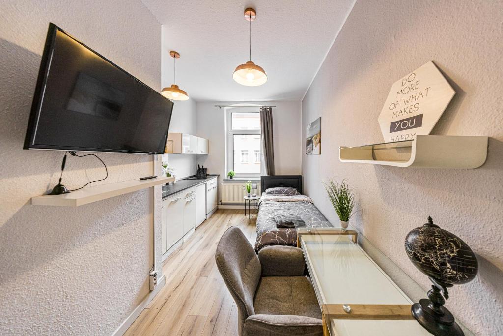 a living room with a couch and a tv on a wall at Moderne Single Apartments Hauptbahnhof in Halle an der Saale